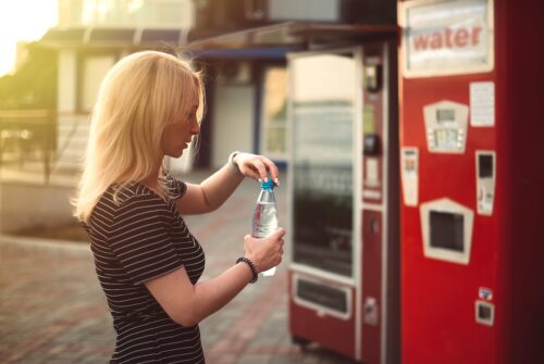 woman getting water from outdoor vending machines
